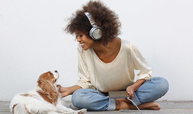 young lady with headphones smiling at cute dog