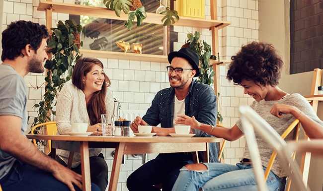 group of people sitting at table drinking coffee and laughing